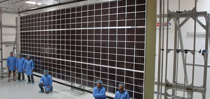 Team di scienziati accanto ad un gigantesco pannello