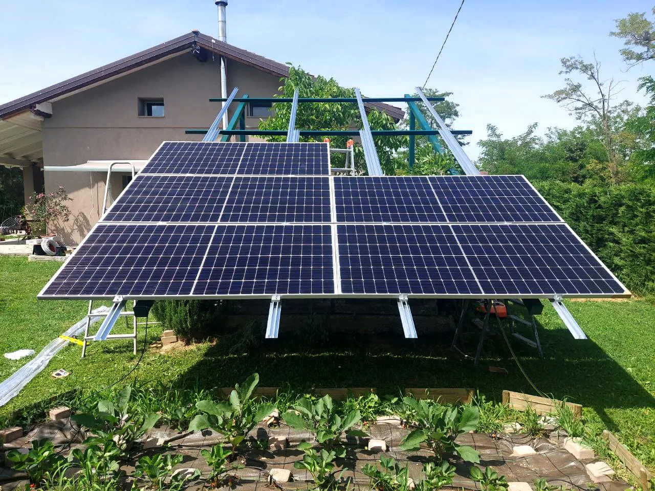Moduli fotovoltaici sulla struttura a terra visti da vicino, con le aiuole coltivate in primo piano