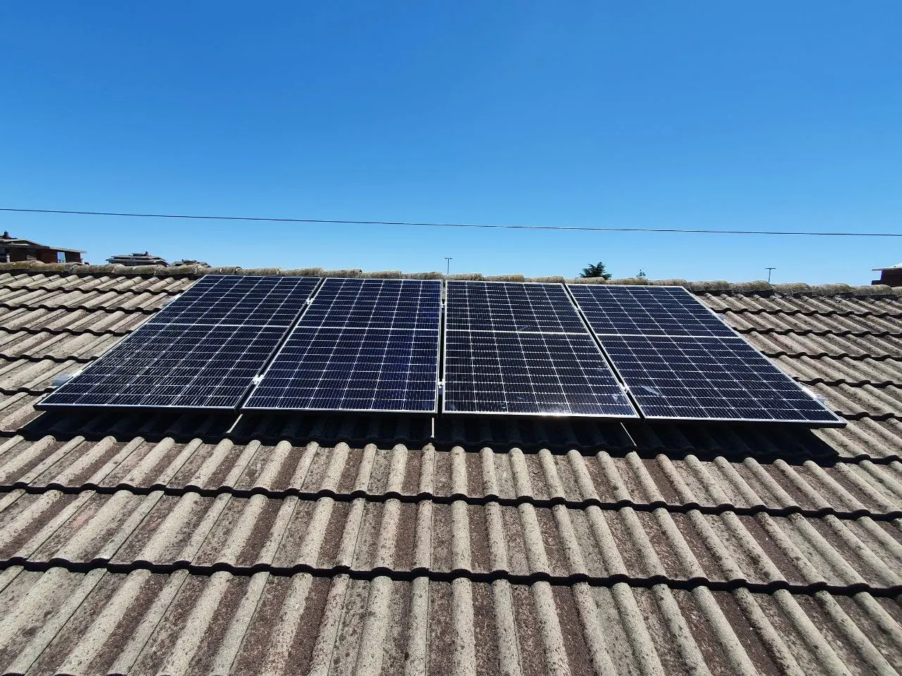 Fila di moduli fotovoltaici sul tetto in tegole di un edificio, vista da vicino con cielo sereno