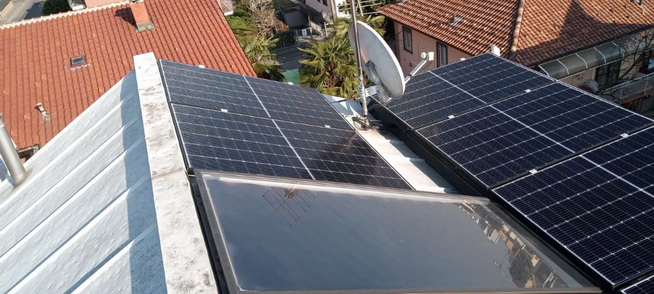 Moduli fotovoltaici e, accanto, un pannello di aspetto diverso su una copertura metallica chiara