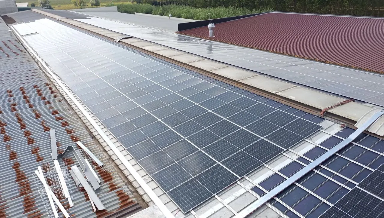 Moduli fotovoltaici su un capannone industriale visti dall'alto, con la copertura in lamiera accanto