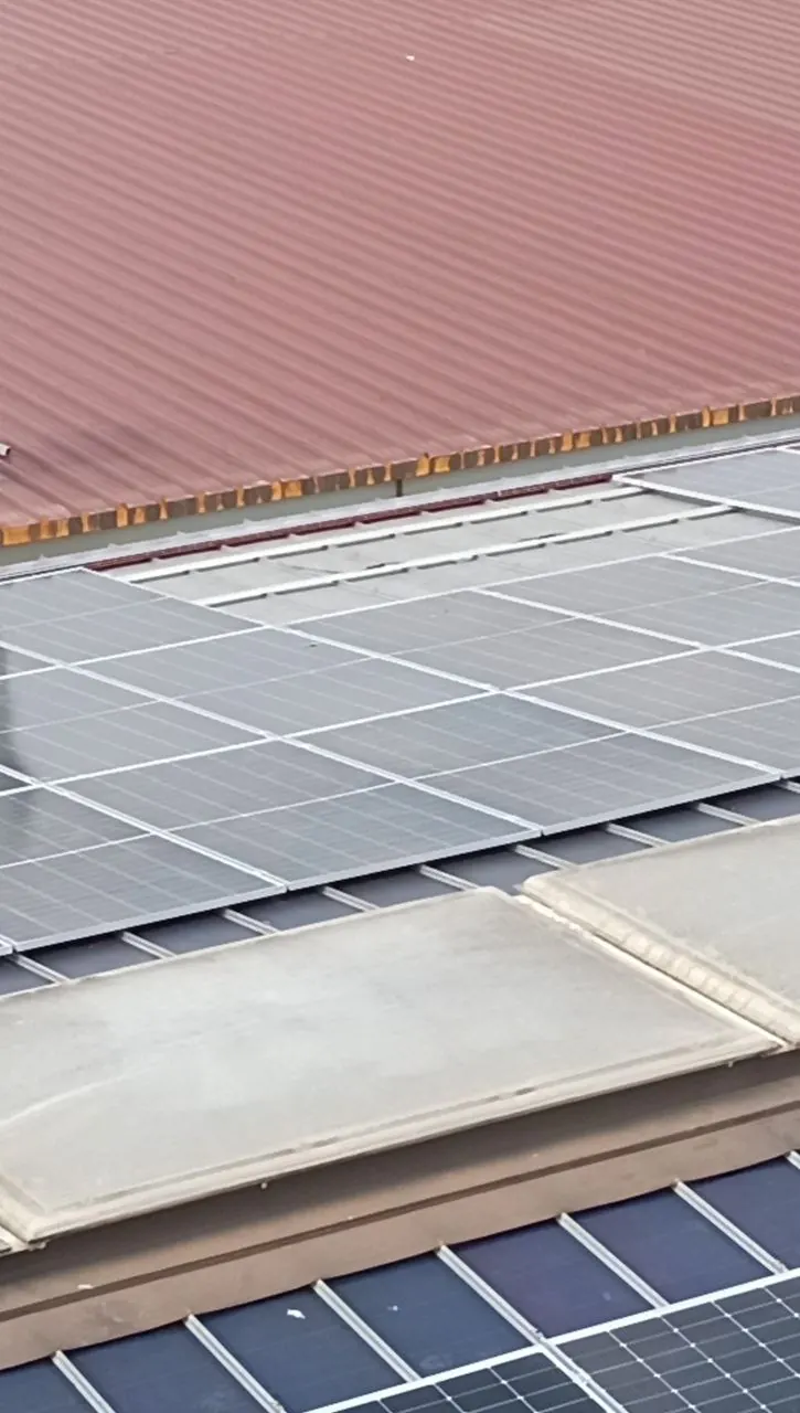 Moduli fotovoltaici accanto alla copertura rossa di un capannone industriale