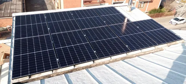 Moduli fotovoltaici su una copertura metallica chiara, con la strada sottostante